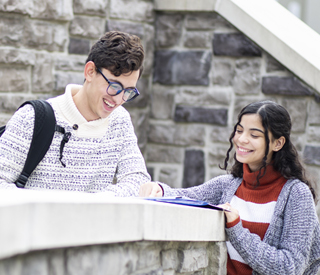 Male and female student reading a book on a ledge at the Woodland Park Campus mobile image