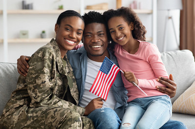 A family of three sitting on a couch, proudly displaying an American flag