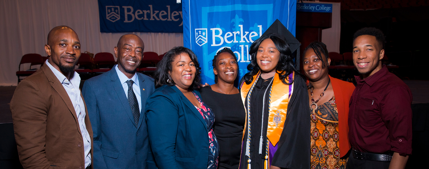 Photo of Berkeley College graduate at Commencement with family.