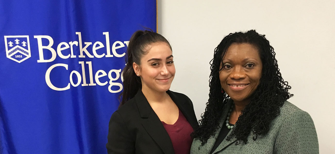 Moya Bansile with female student in front of Berkeley College Banner