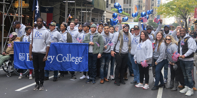 Group of Berkeley students at Veterans Day Parade in NYC holding Berkeley College flag