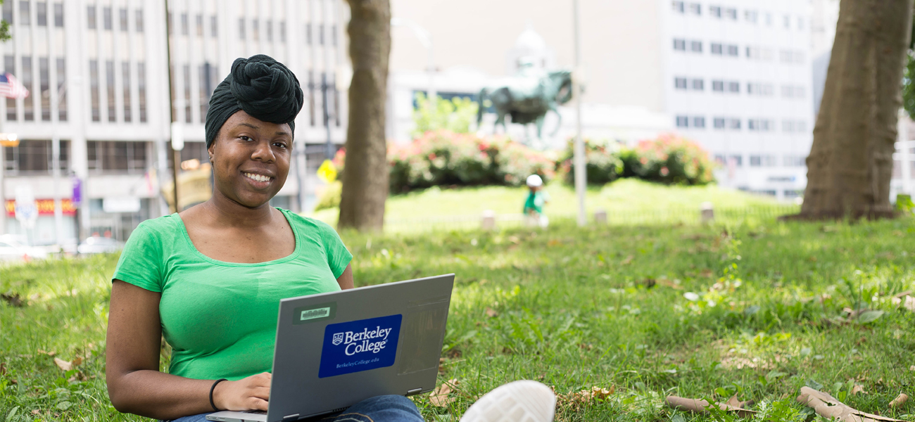 Female student on laptop sitting outside