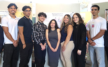 A group of diverse students stands in a line and smiles at the camera.