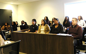 A group of students sits at a jury panel to act as jurors in a mock trial.