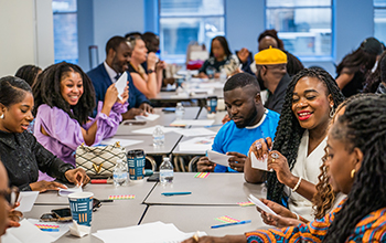 A group of people smile and participate in a workshop activity.
