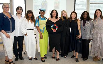 A group of diverse people stand in front of the camera and smile at a United Nations (UN) event.