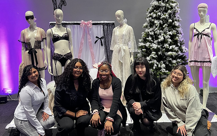 students crouch in front of mannequins at a trade show