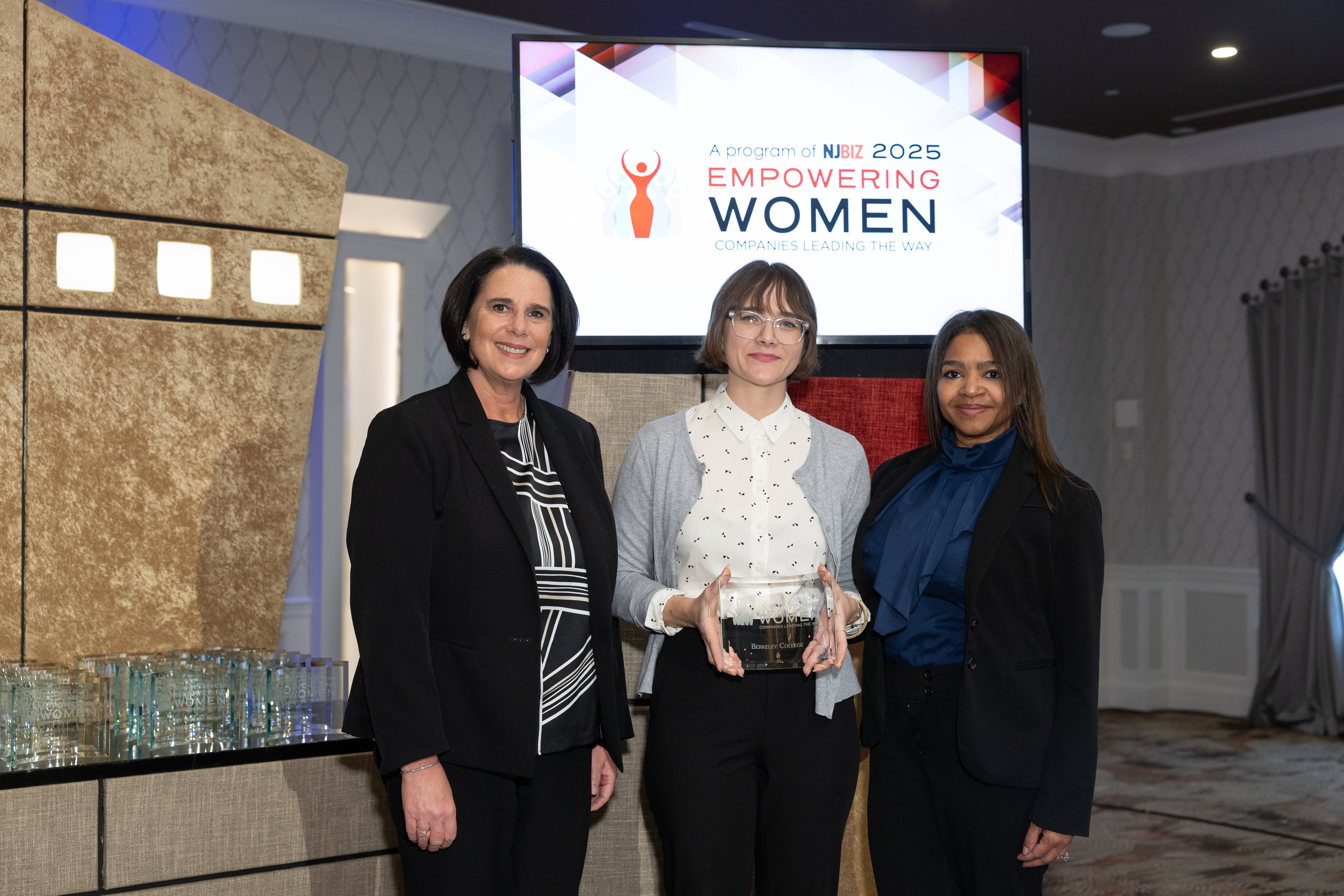 three women stand on a stage