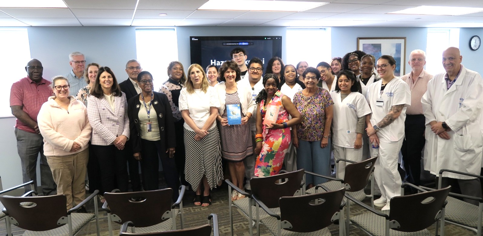 A diverse group of students, faculty, and author Kim Downey smile a the camera.