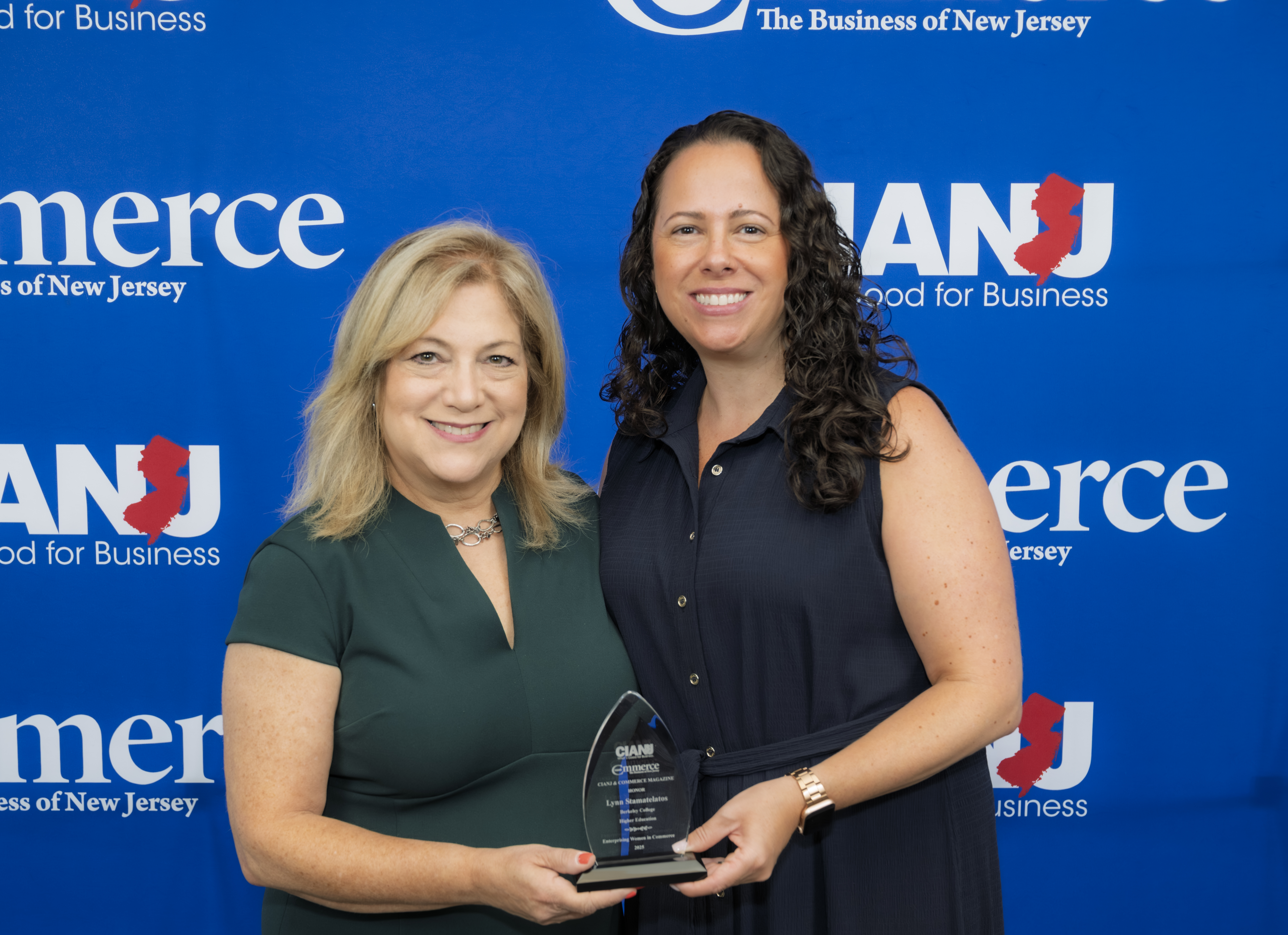 Two women smiling and holding a trophy