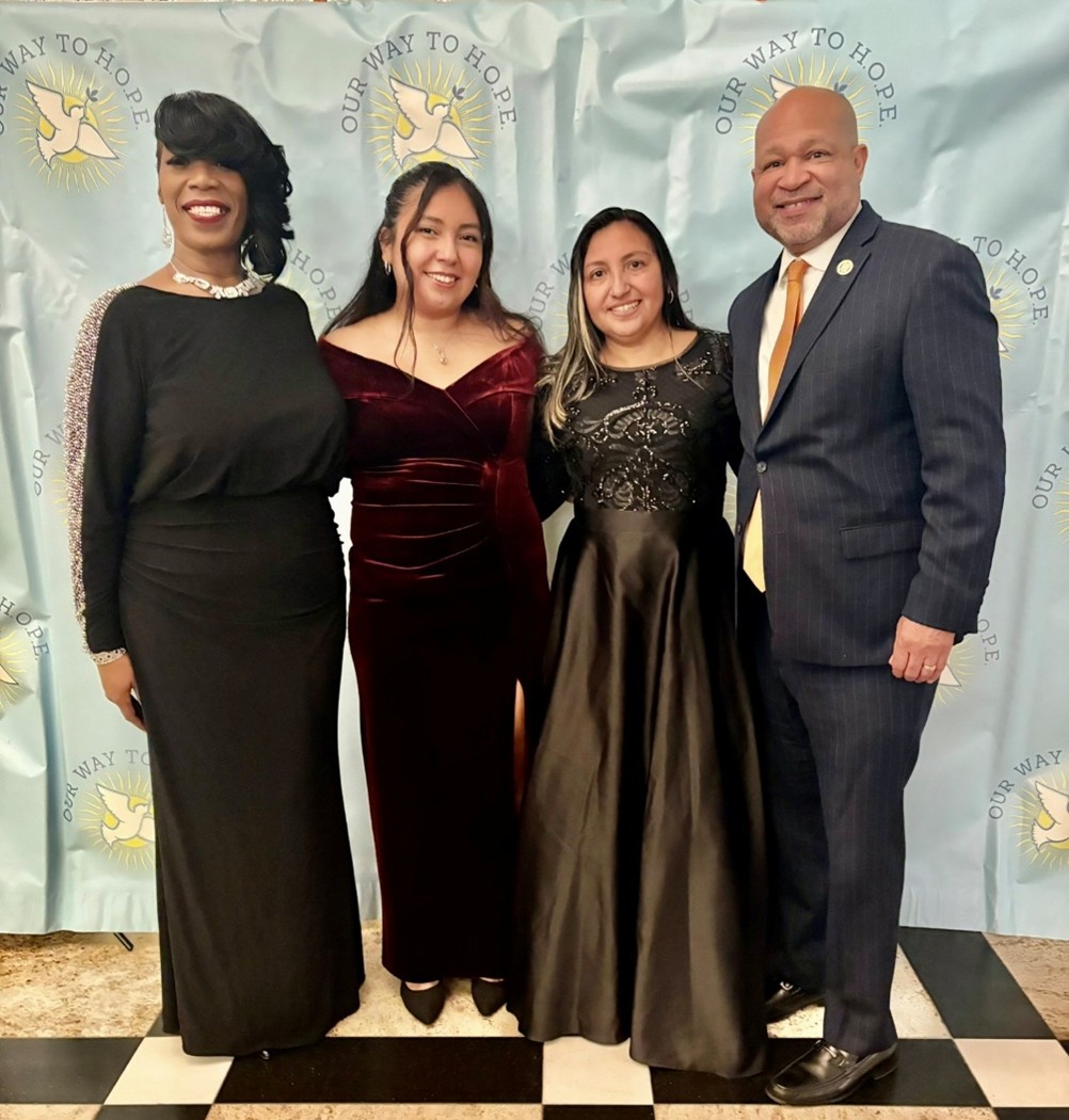 Four people stand and pose for a photo.