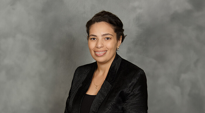 A professional woman dressed in a black blazer and black shirt, showcasing a sleek and sophisticated appearance