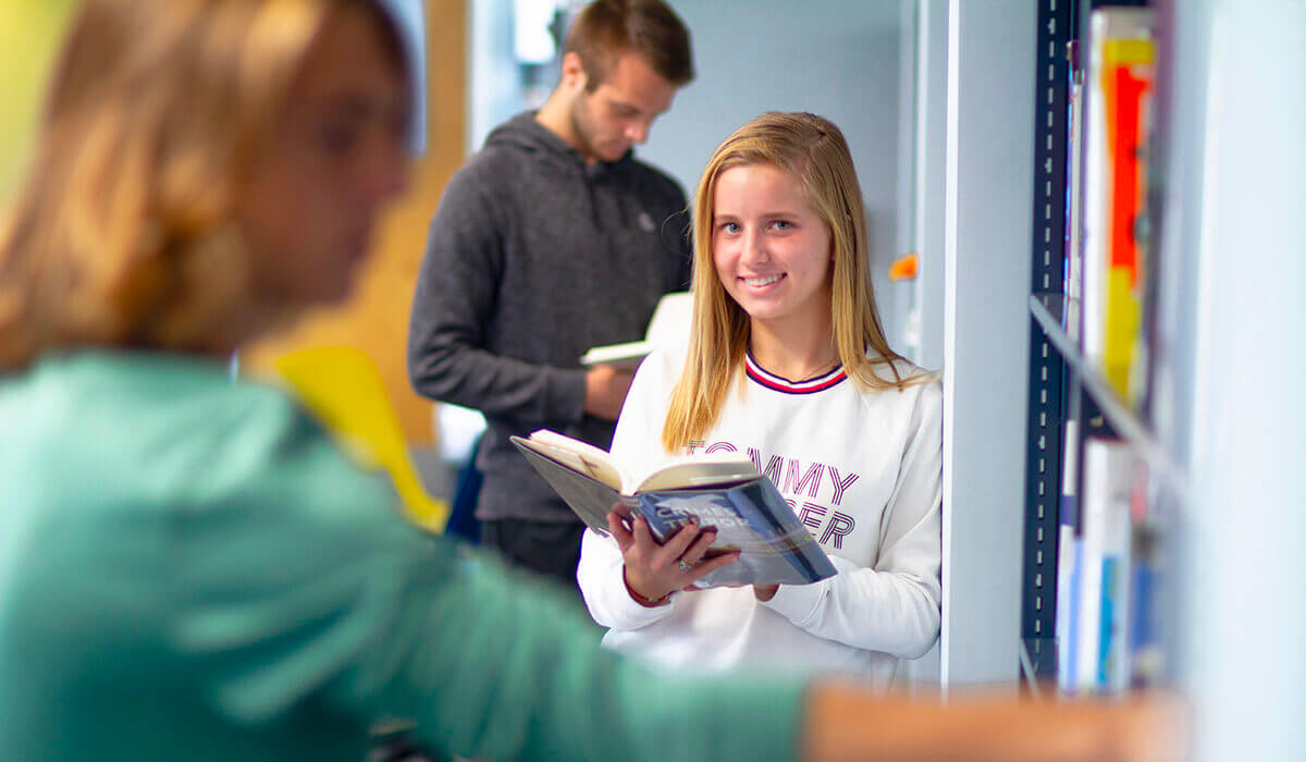 Student, Olivia Strama in library with book in hands