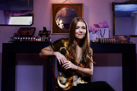 Female sitting in chair smiling in front of makeup kits