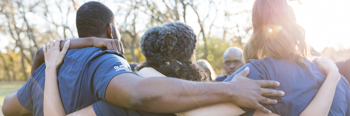 Image of people with their arms wrapped around each other's shoulders
