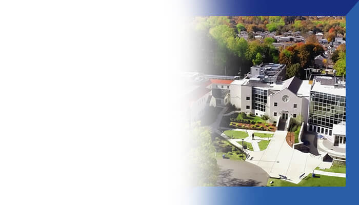 Aerial view of a historic building with intricate architecture, surrounded by urban landscape and soft gradient background.