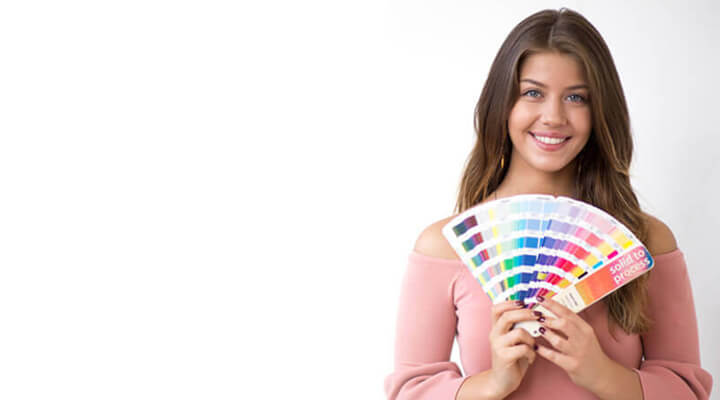 A woman holding a color swatch, examining different shades
