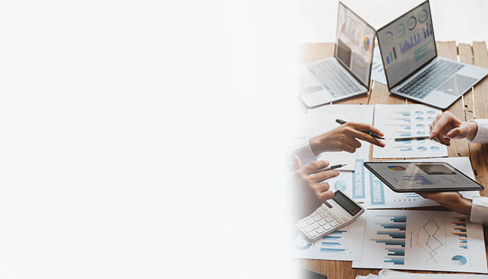 Group of business professionals working on laptops and papers in a modern office setting
