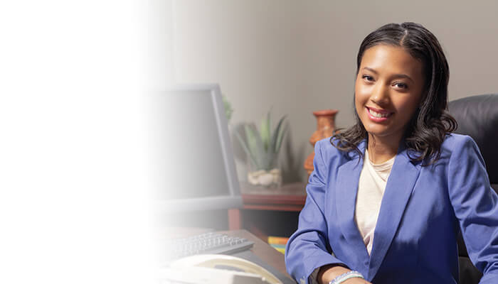 a woman dressed in a business suit, sitting at her desk, radiating positivity and professionalism
