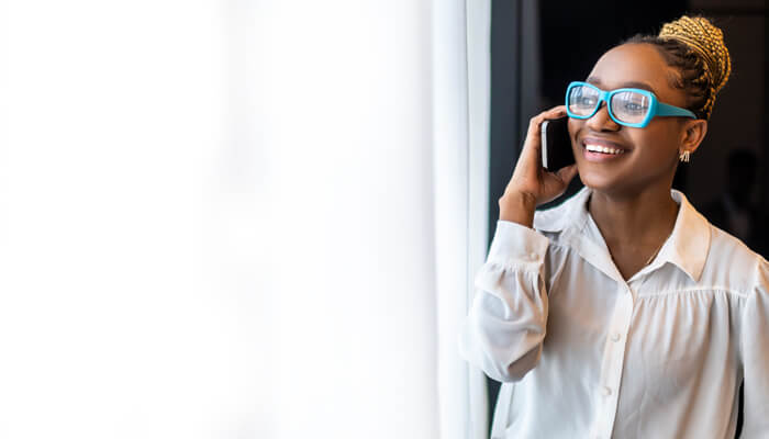 A woman wearing glasses while speaking on a cell phone