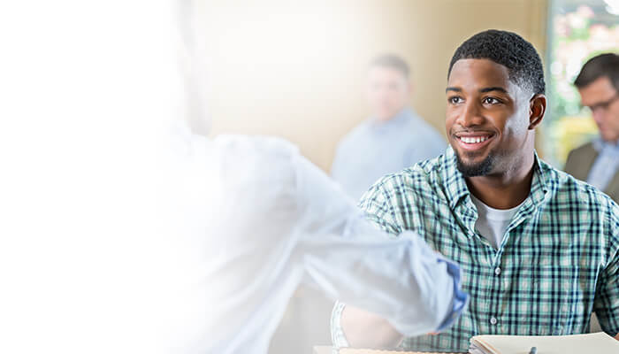 A man smiles joyfully at a table surrounded by friends, creating a warm and inviting atmosphere