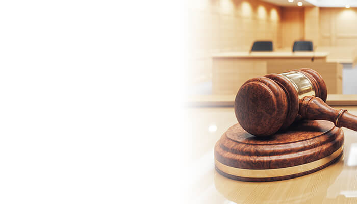 A wooden gavel rests on its block in a brightly lit courtroom, symbolizing justice and legal proceedings.