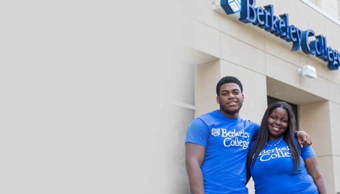 Two young people in blue shirts standing in front of a building