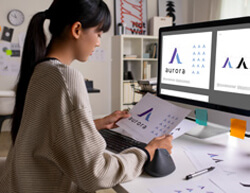 A woman focused on her work, using a computer with two monitors in a modern office setting