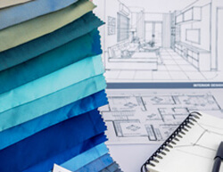 A stack of colorful fabric samples beside an open notebook on a wooden surface, showcasing design ideas and textures