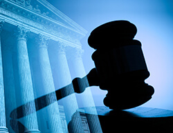 Silhouette of a gavel in front of a classical courthouse, symbolizing justice and legal proceedings