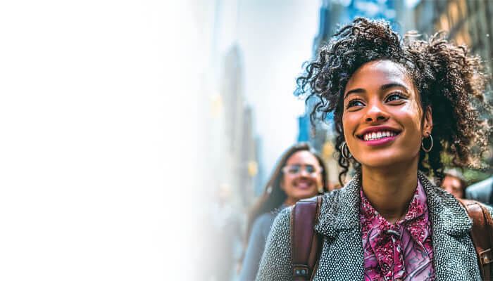 Smiling student with a backpack walking through New York City.