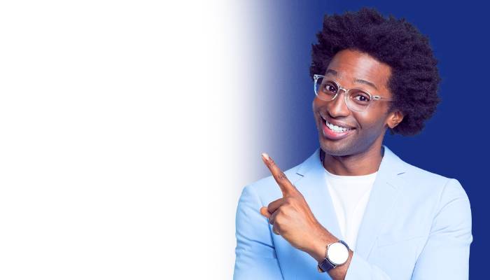 Smiling person with curly hair, wearing glasses and a light blue blazer, pointing with one finger. The background is a gradient of blue to white.