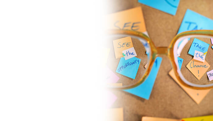 A pair of glasses resting on a bulletin board, surrounded by various notes and reminders pinned to the surface