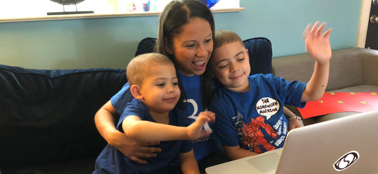 Photo of Dr. Melissa Baralt working on a laptop with her 2 boys.