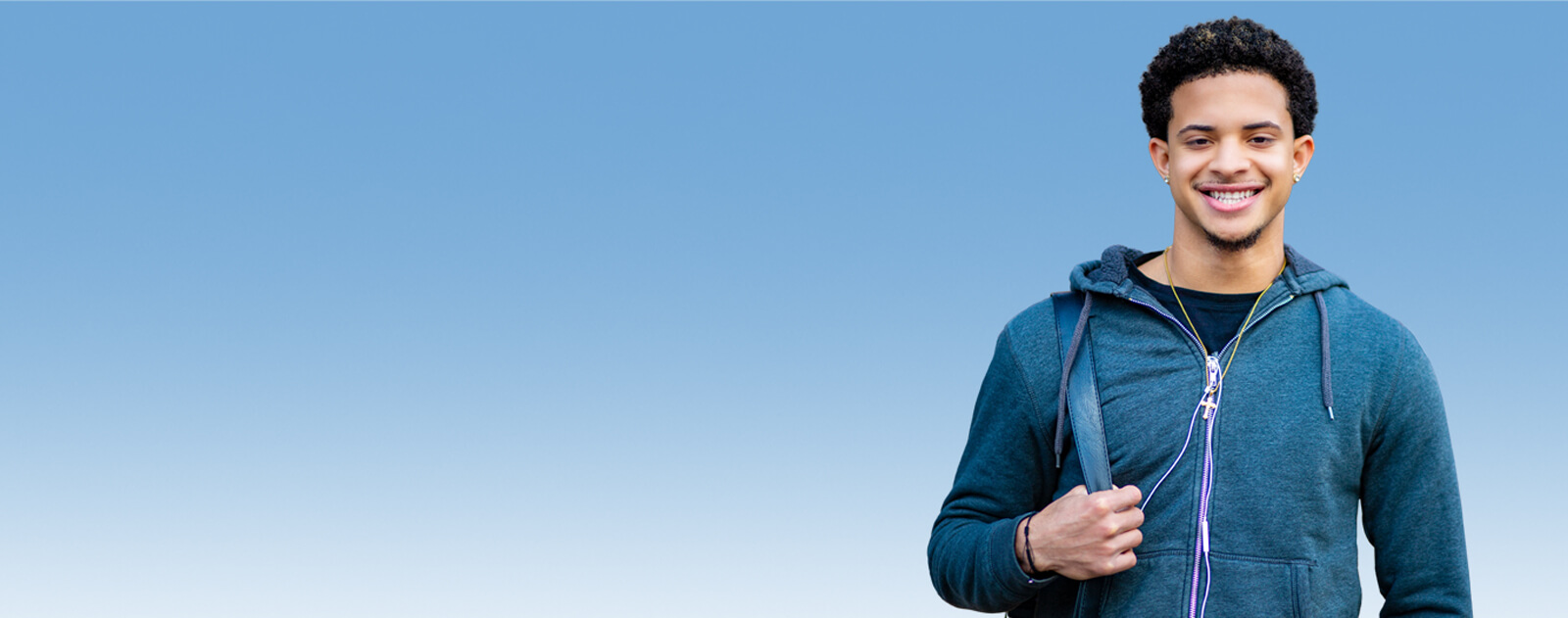 Image: a young male smiling in front of a blue background