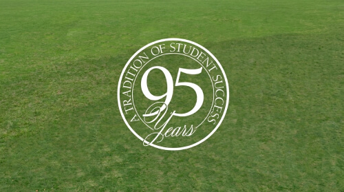 A green field with a circular logo celebrating 95 Years: A Tradition of Student Success prominently displayed in the center