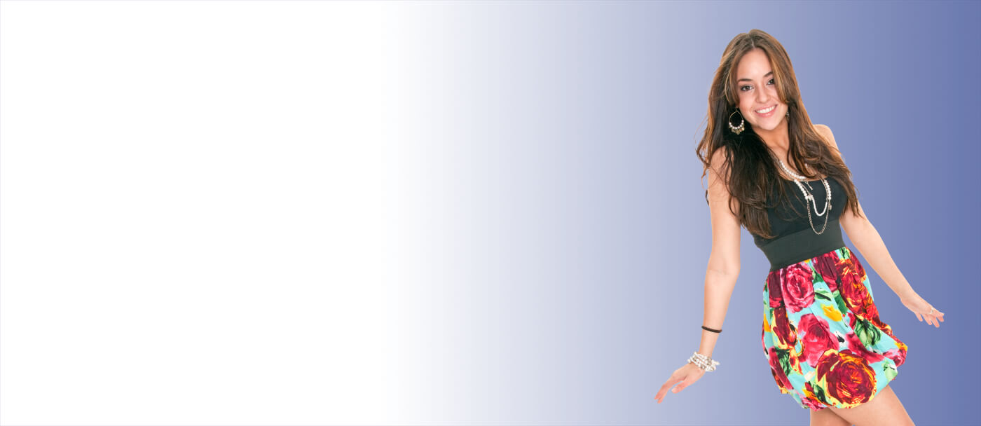 Smiling woman in a colorful floral skirt and black top standing against a gradient white to blue background, exuding a joyful, playful energy.