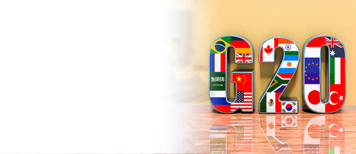 3D letters 'G20' decorated with member country flags stand against a light yellow wall. The polished floor reflects the vibrant colors, conveying unity.