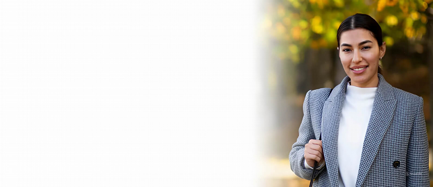 A woman in a business suit displays a warm smile, representing success and professionalism in her career.