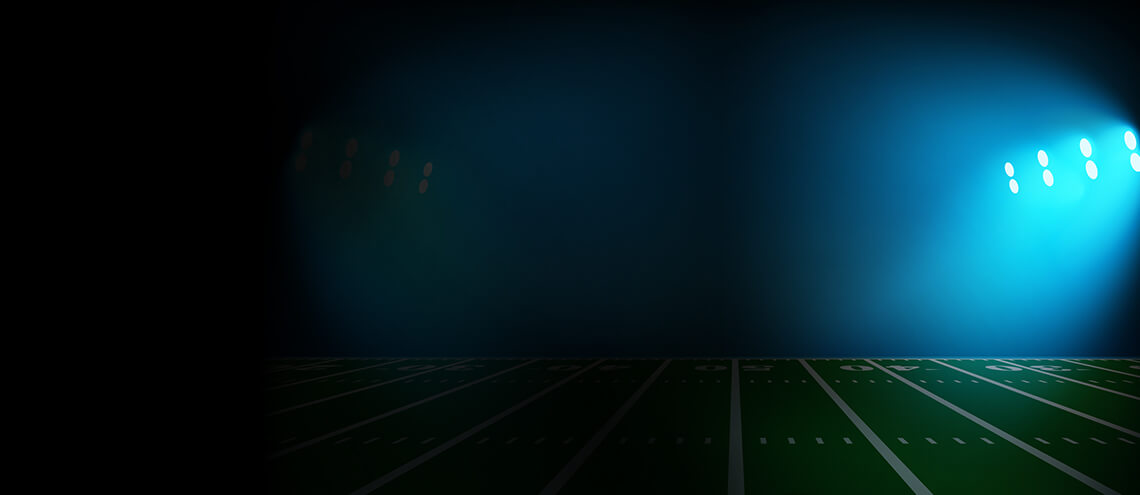 An illuminated American football field featuring bright lights and a focused spotlight, ready for an evening game