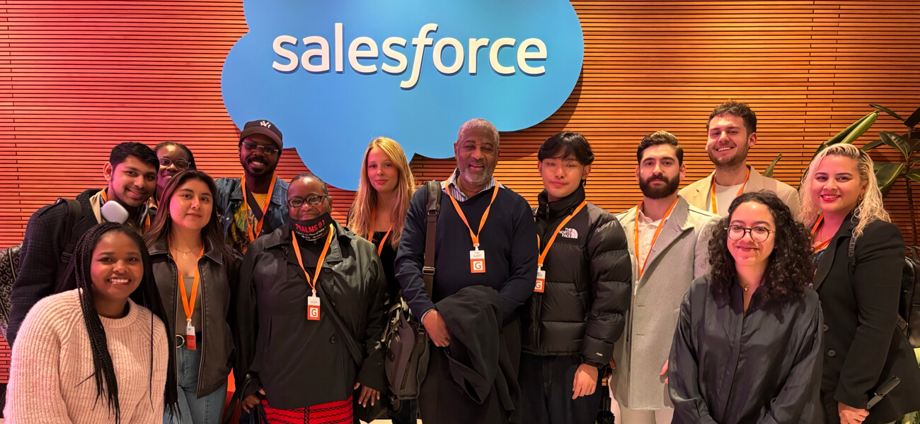 Group of individuals posing together in front of a Salesforce logo, showcasing a diverse gathering in a professional setting.