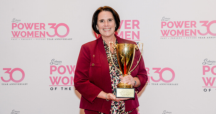 A woman in a red suit proudly holds a trophy showcasing her achievement and confidence