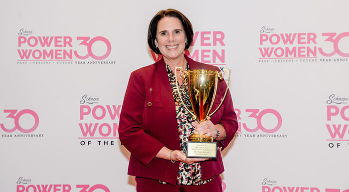 A woman in a red suit proudly holds a trophy showcasing her achievement and confidence