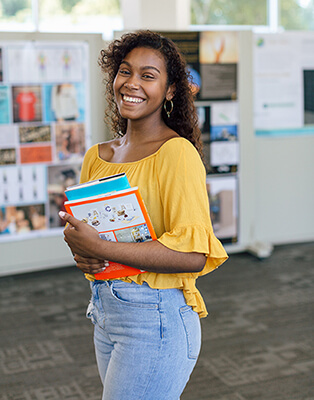 Gleny Bravo smiling carrying her books