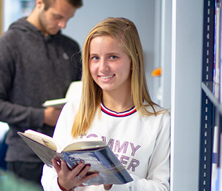 Female student with book in the library mobile image