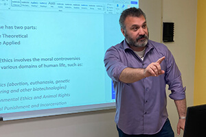 A man presents information to an audience, standing before a screen filled with engaging visuals.