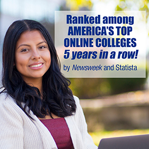 A woman working on a laptop smiles at the camera.