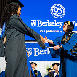 A woman receives a diploma from a college president.