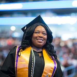 A woman in a graduation gown smiles