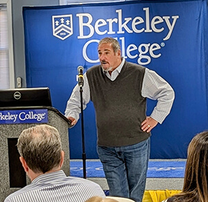 A man stands at a podium, delivering a presentation to an audience at a professional conference